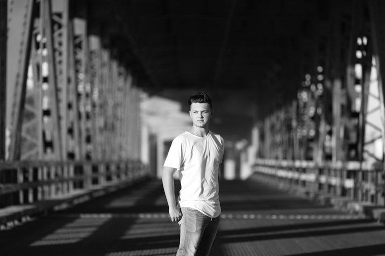 dramatic striking picture of senior boy on old metal bridge