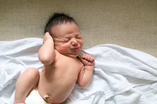 cute baby making scrunchy face while stretching authentic newborn photography