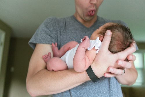 dad making funny face at newborn during in-home lifestyle baby session