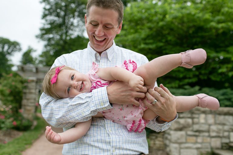 fun real moment of girl held by dad in park