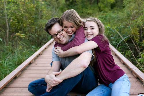 girls bear hugging dad during authentic sweet family photo session