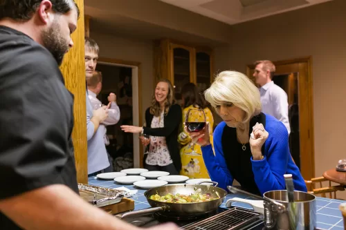 KC documentary photographers photo of chef cooking dinner at birthday party while surprised lady looks on