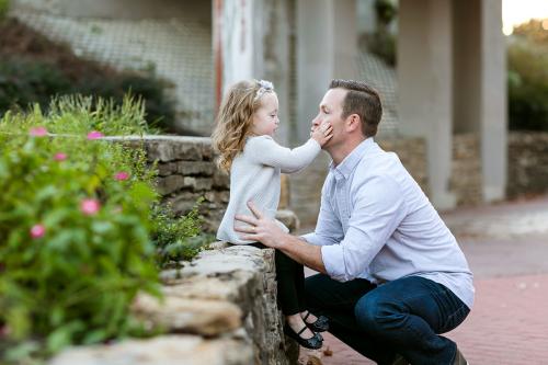adorable real moment between daddy and daughter touching his cheeks