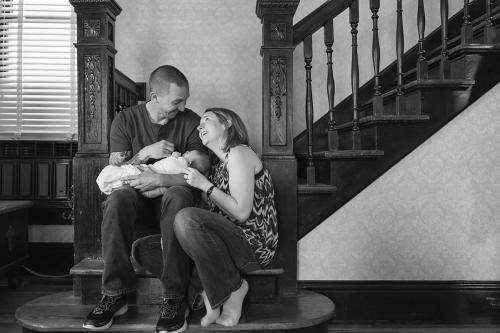 authentic joyful family holding newborn on stairs in-home session