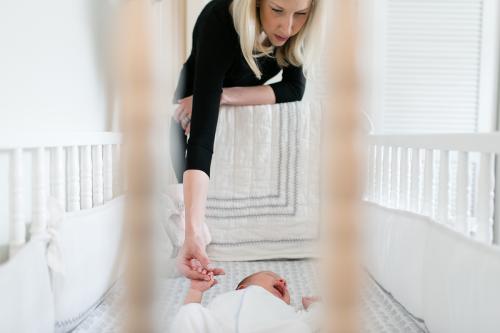 documentary newborn photographers authentic story moment mom holding baby's hand in crib