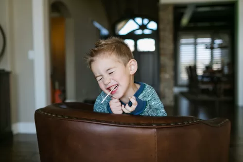 funny kid with sucker in mouth in-home real moment documentary photo