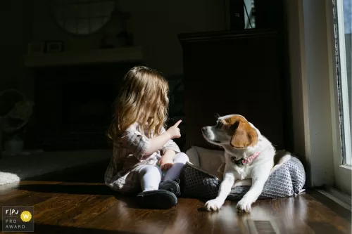 girl talking to dog with finger real life unposed photo family photojournalist award