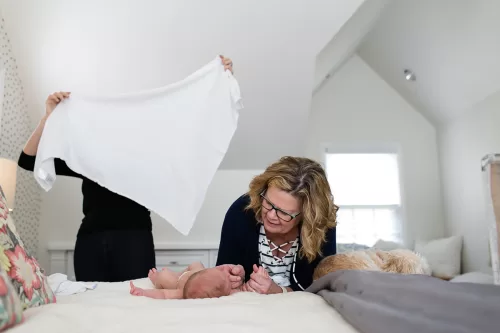 grandma with newborn baby and mom folding diaper sweet genuine moment