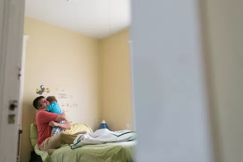 in-home family documentary session dad hugging son on bed
