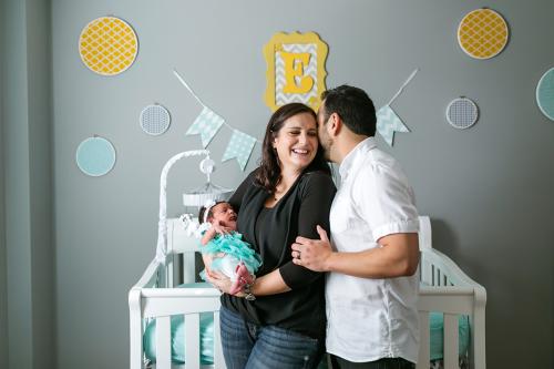 joyful genuine moment of mom and dad holding baby in nursery picture