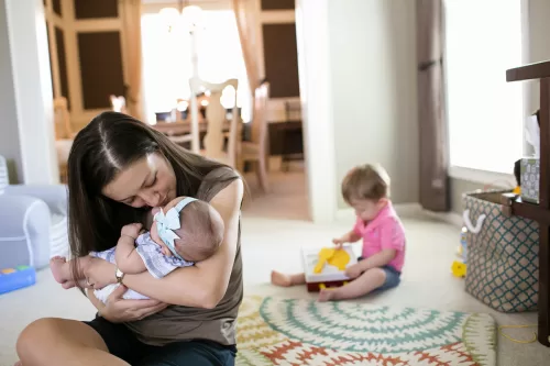 mom holding baby with son playing on floor sweet family moment