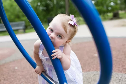 real candid fun moment of kid biting playground equipment with funny face photo