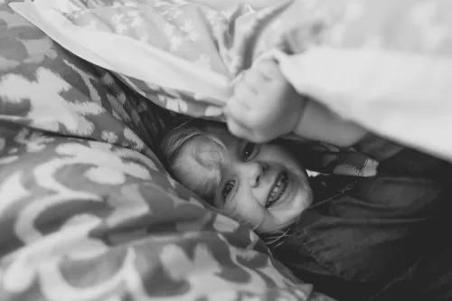 silly funny girl hiding under blanket real moment documentary photo