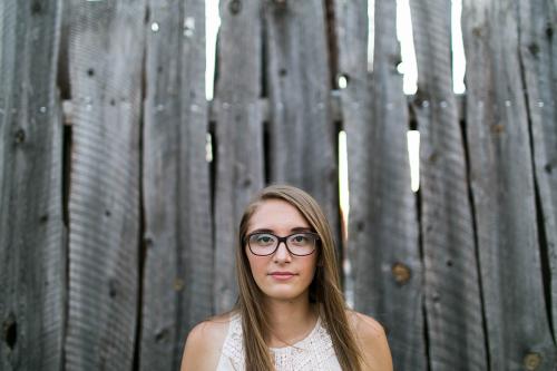 stunning senior headshot in front of wood fence