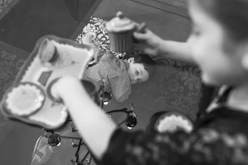 sweet genuine candid moment of girl playing tea and brother watching photo